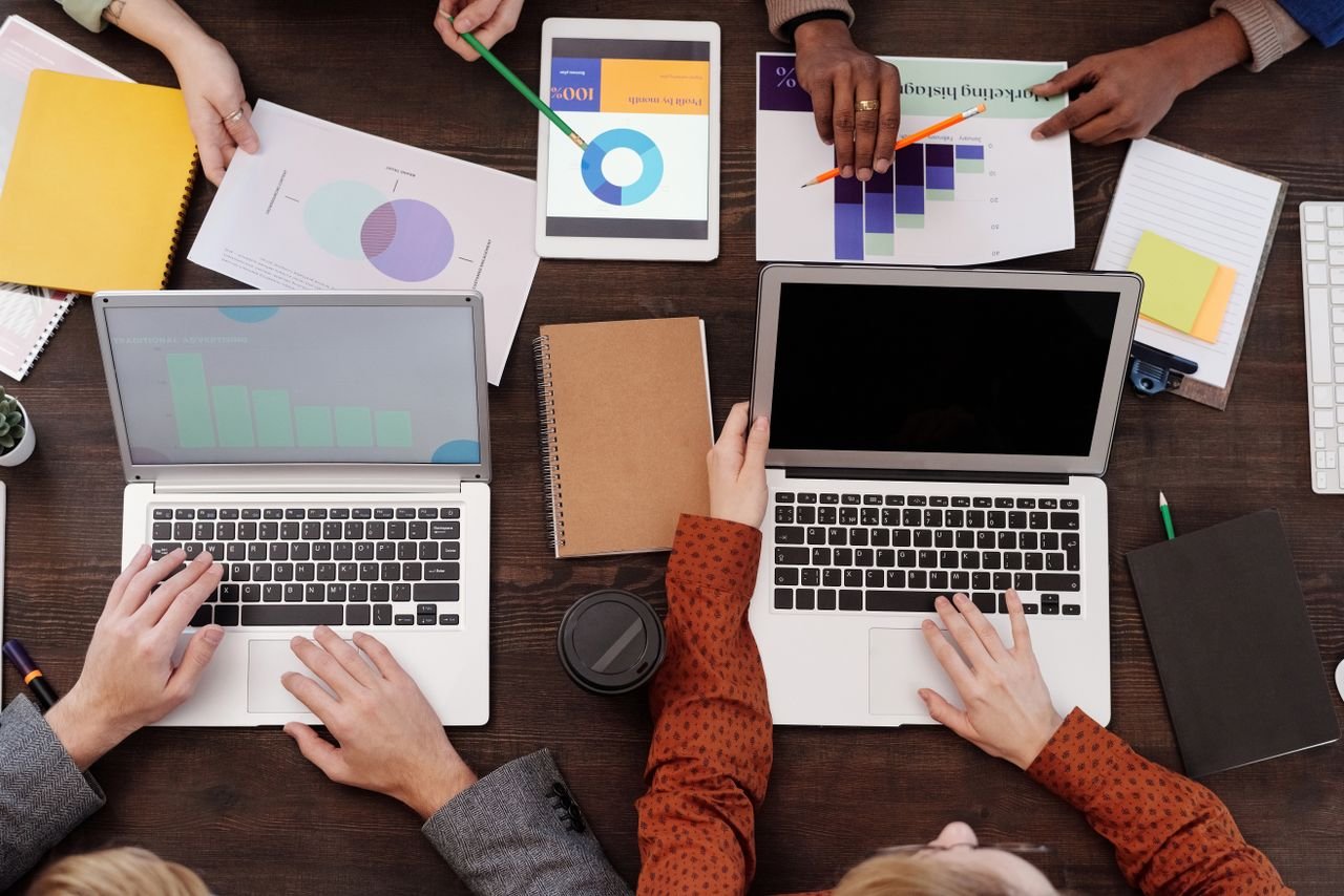Overhead view of a team discussing digital marketing strategies with laptops and charts.